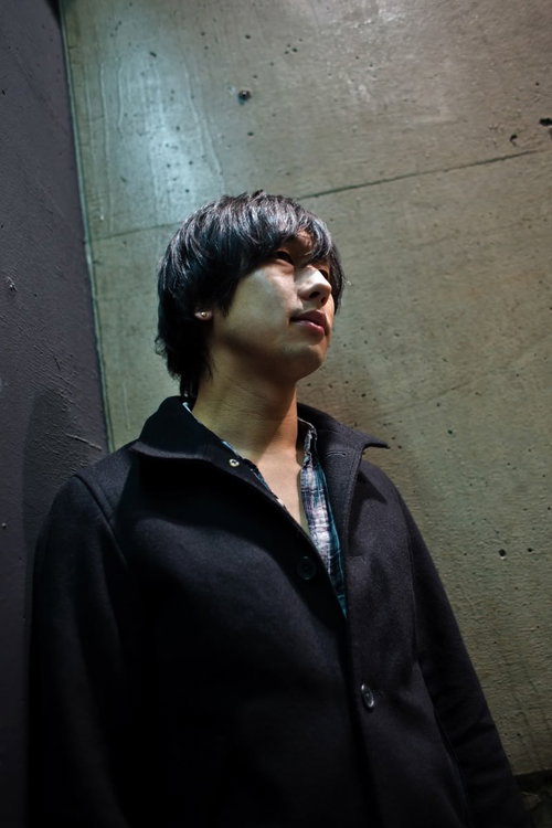 冷たいコンクリートの壁にもたれてうつむく疲れた男性