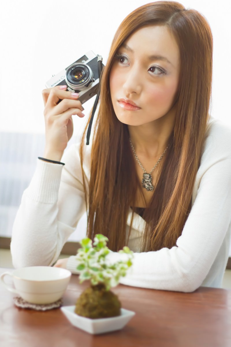 レトロカメラで肘をつく女性［モデル：北野佑々］