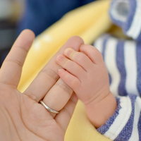 母親の人差し指をぎゅっと握りしめる赤ちゃんの小さな手の写真