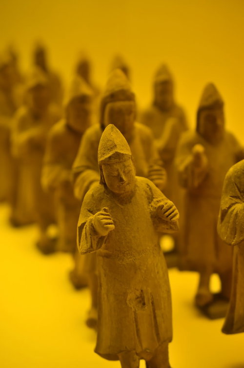 棚の上に一列に連なって並ぶ小さな土人形のコレクション