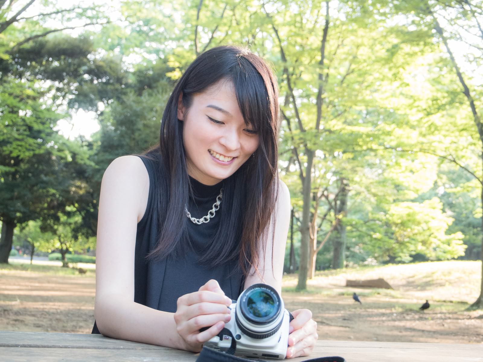 公園で一眼レフカメラを構える女性［モデル：たけべともこ］