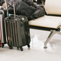 空港のロビーに置かれた旅行用キャリーケースの写真