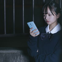 スマホを操作して浮気調査をする女子高生探偵の写真