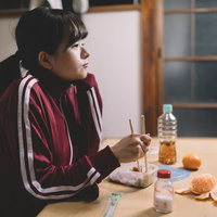 貧困から抜け出せないジャージ姿で食事をする女子学生の写真