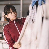 室内干しをする赤いジャージの貧乏女学生の洗濯風景の写真