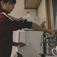 溜まった洗い物をする貧乏学生がアパートで食器を洗うの写真