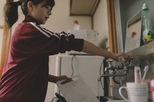 溜まった洗い物をする貧乏学生がアパートで食器を洗う