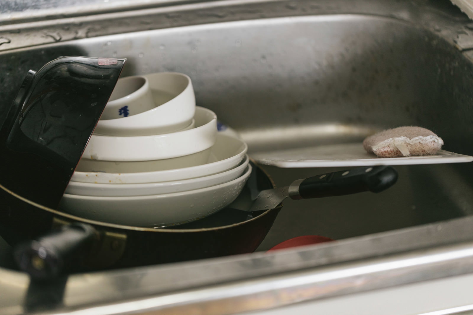シンクに積まれた白い食器と黒いフライパン