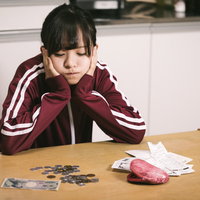 今月も浪費が止らない、机の上の残り少ない現金と請求書の写真