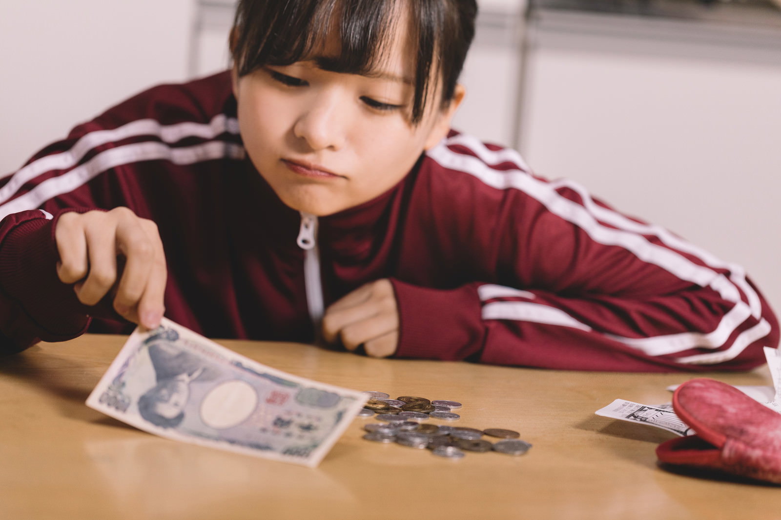 テーブルで千円札と硬貨を数える子ども［モデル：千歳］