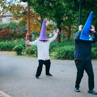 布団たたきで怪しい三角コーン（男）を撃退する三角コーン（女）の写真