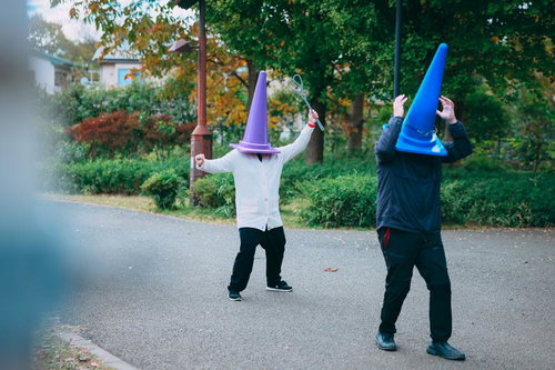 布団たたきで怪しい三角コーン（男）を撃退する三角コーン（女）