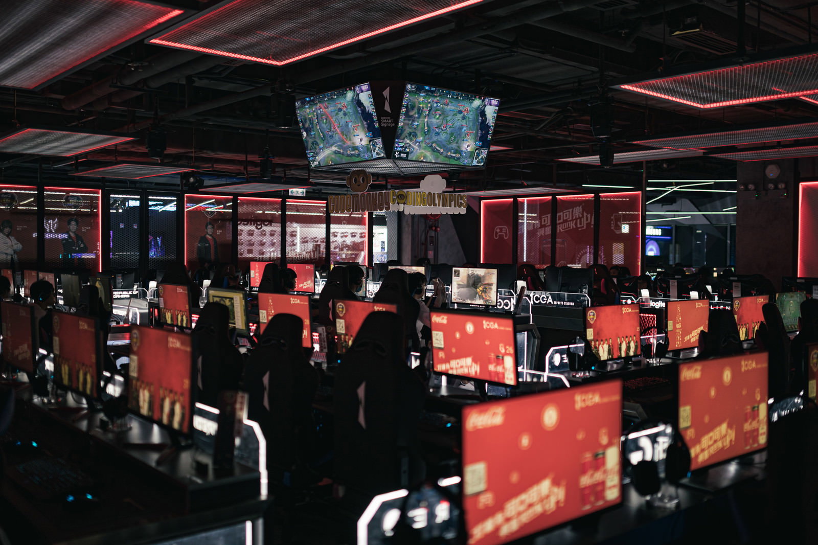 赤いライティングが印象的なeスポーツ施設で複数のゲーミングモニターが並ぶ様子