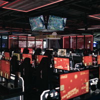 赤いライティングが施された大型eスポーツ施設「CGA」に並ぶゲーミングモニターの写真