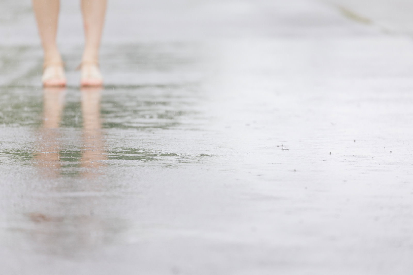 雨上がりの水たまりに映る足元の反射と濡れたアスファルト