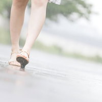 雨の日、濡れた路面を歩く女性の足元と水たまりの写真