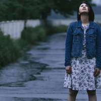 雨に打たれてびしょ濡れになる女性の悲しい表情の写真