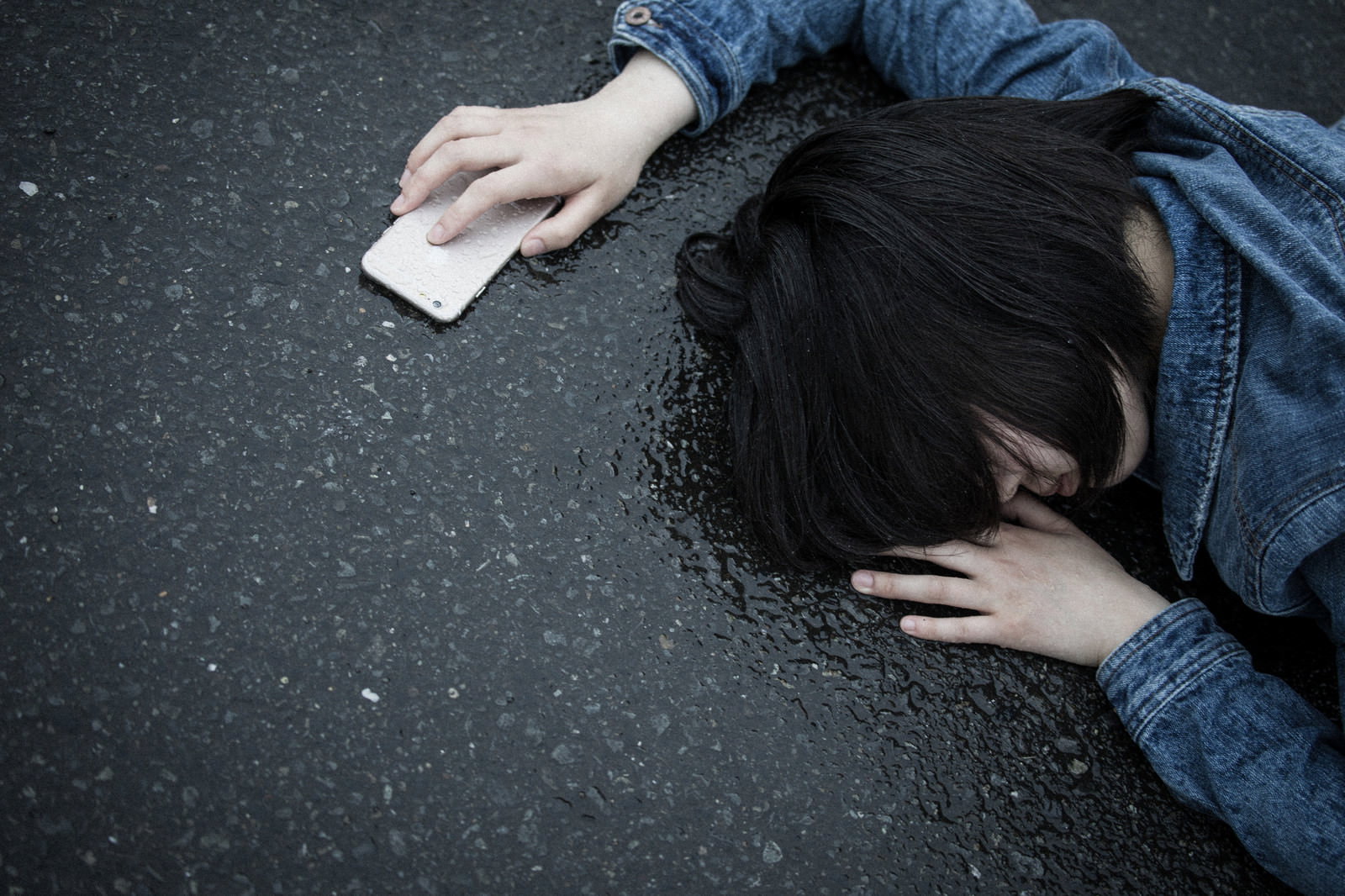 雨に濡れたアスファルトで歩きスマホをしながら転倒した女性［モデル：佐竹PP］