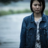 雨に濡れるデニムジャケットの女性の写真