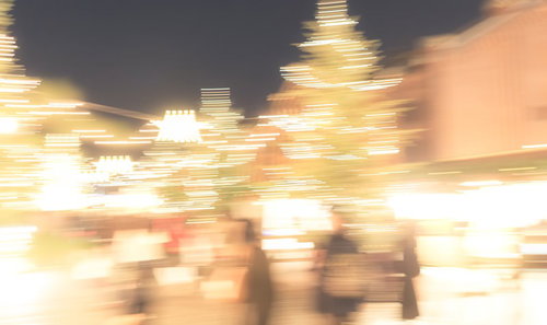 人混みに映るイルミネーションの光跡と夜間の商業施設