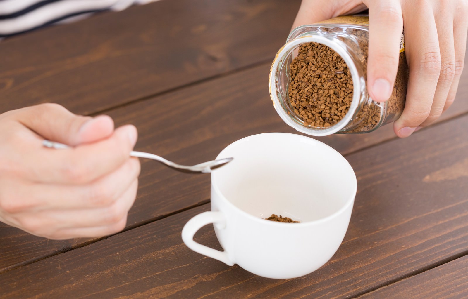 インスタントコーヒーをカップに注ぐ手元［モデル：大川竜弥］