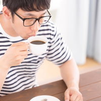コーヒーを吹きながら飲む猫舌のサードウェーブ系男子の写真