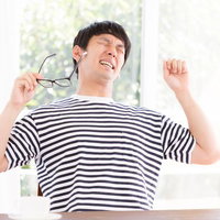 作業の合間に伸びをする男性、眼鏡を手に持ちあくびをするの写真