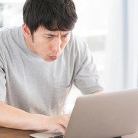 あの日見たお気に入りの動画が見つからないとノートパソコンで困る男性の写真