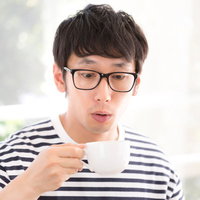 サードウェーブコーヒーの美味しさに驚く眼鏡をかけた男性の写真