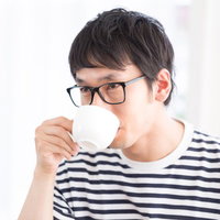 眼鏡をかけた男性がコーヒーを飲むスウィーツのマリアージュの写真