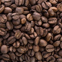 敷き詰められた焙煎済みのコーヒー豆、黒褐色の粒が光沢を放つの写真