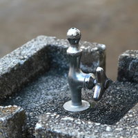 緑の中に置かれた公園の水飲み場の写真