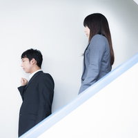 オフィスの非常階段を駆け下りながら打ち合わせする男女のビジネスパーソンの写真