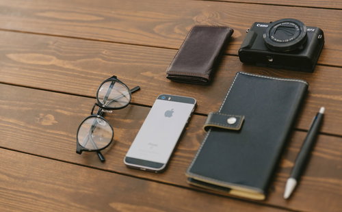 取材に必要なカメラや手帳が木目のテーブルに置かれた様子