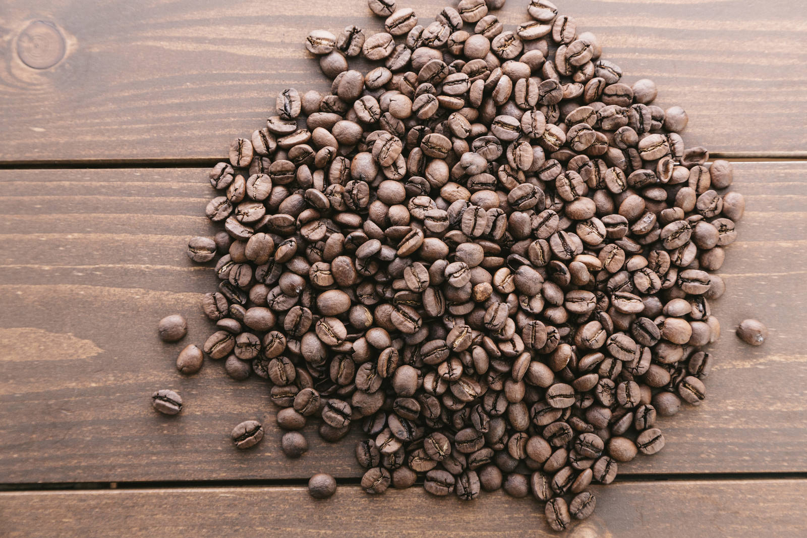 木目のテーブルに山盛りになったコーヒー豆