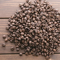 木目のテーブルに広げたコーヒー豆の写真