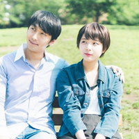 公園のベンチでまだ距離感のある初々しいカップルの写真