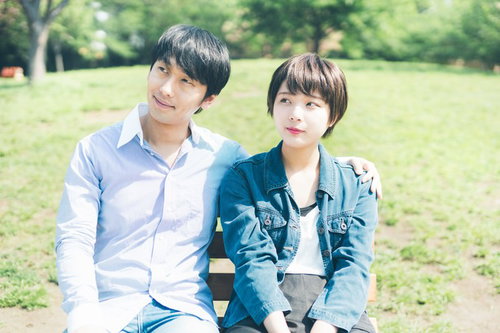 公園のベンチでまだ距離感のある初々しいカップル