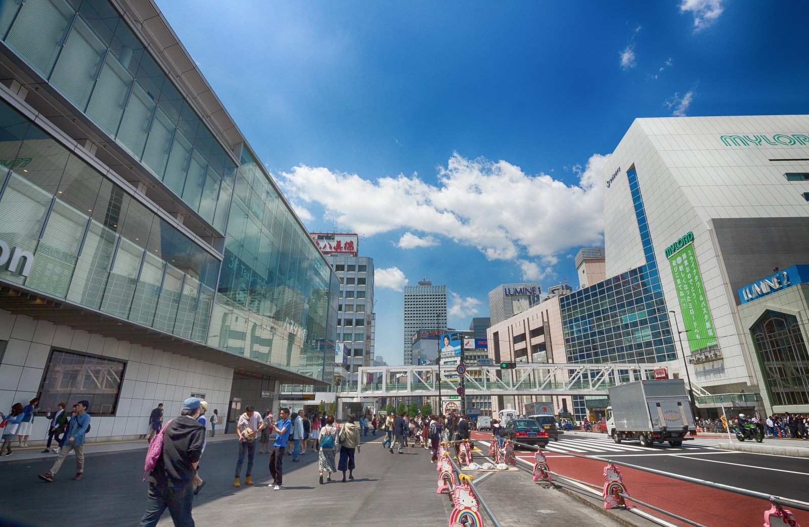 新宿駅南口駅前で青空の下、多くの人が行き交う都市風景