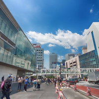 新宿駅南口駅前の人混みと青空、横断歩道と高層ビルの写真