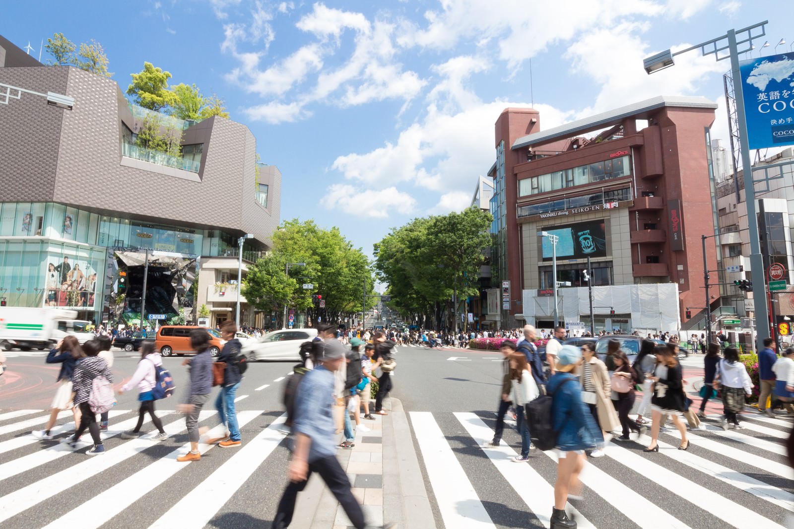 原宿の神宮前交差点で横断歩道を渡る大勢の人々と周辺の建物