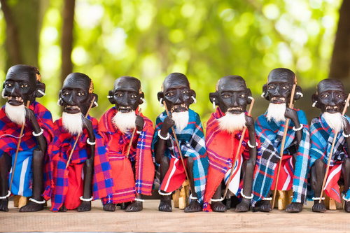 赤と青のチェック柄布を身に纏った木彫りの人形たち