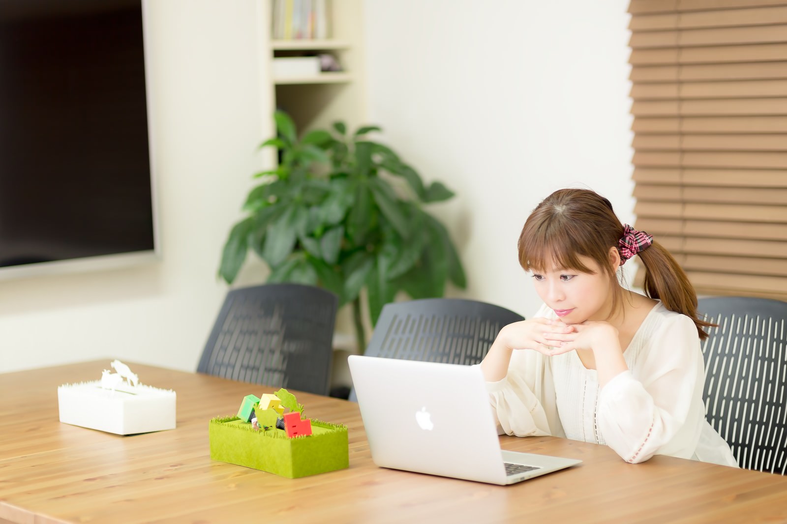 清潔感のあるコワーキングスペースでノートパソコンを使って作業する若い女性［モデル：暢子］