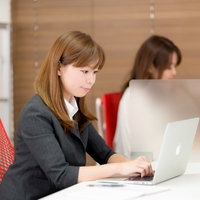 コワーキングスペースでパソコン作業するスーツの女性の写真