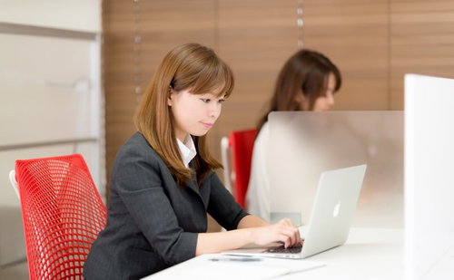 コワーキングスペースでパソコン作業するスーツの女性