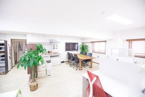 木製テーブルとキッチンのある明るいオフィス