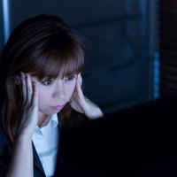 明日の朝が納期！モニターを見つめる残業中のOLの写真