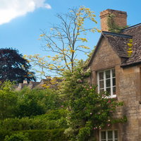 蔦が絡まるレンガ壁と白い窓のウィンチクームの住宅の写真