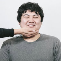 タプタプスマイル、グレーのTシャツで手を頭に組んだ男性の写真