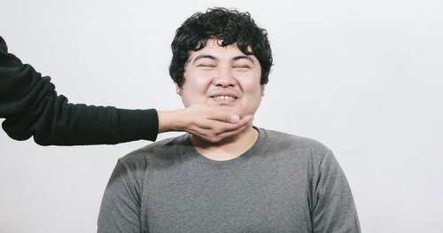 タプタプスマイル、グレーのTシャツで手を頭に組んだ男性